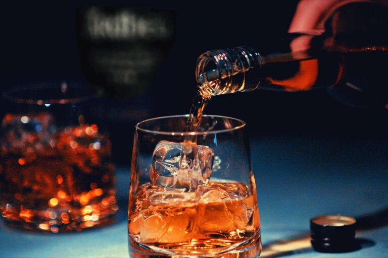 Pouring bourbon into a glass with ice cubes